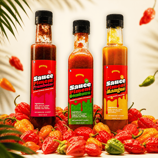 Le Pack de trois bouteilles sauce pimentée  270g (mangue, framboise, combawa) dans un décor exotique avec des piments antillais